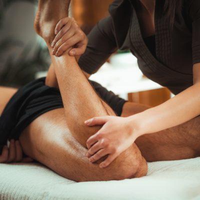 Physiotherapist_Massaging_Male_Patient_With_Injured_Leg_Muscle_Sports_Injury